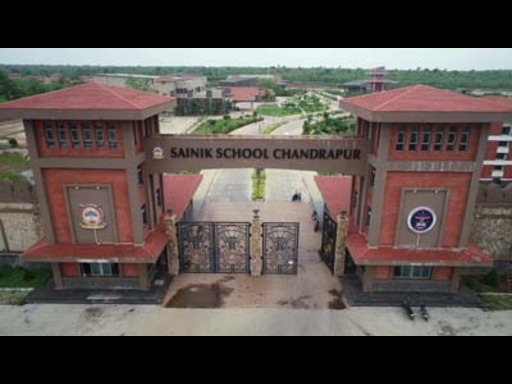 View of Sainik School Bijapur in Karnataka, featuring its large campus with academic buildings, sports facilities, and well-maintained lawns. Students in military uniforms are seen walking across the grounds, with the backdrop of open skies and surrounding greenery, reflecting a disciplined and focused environment.