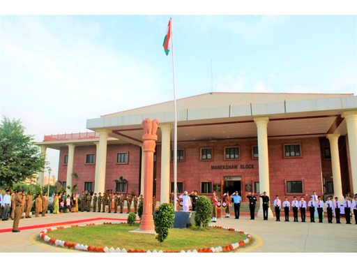 View of Sainik School Jhunjhunu, Rajasthan, featuring its large campus with modern academic buildings, sports facilities, and open grounds. Students in military uniforms are seen walking or participating in activities, with the backdrop of the desert landscape and a serene, disciplined atmosphere.