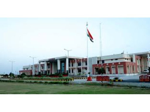 View of Sainik School Jhansi, Uttar Pradesh, showcasing its expansive campus with modern academic buildings, sports grounds, and well-maintained lawns. Students in military uniforms are seen walking or engaging in various activities, with a backdrop of arid landscapes and a disciplined, focused atmosphere.