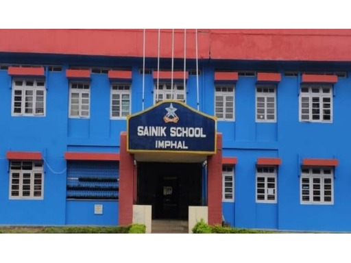 Scenic view of Sainik School Imphal in Manipur, featuring its large campus with academic buildings, sports facilities, and lush green landscapes. Students in military uniforms are seen walking along pathways, with the backdrop of hills and a serene, disciplined atmosphere.