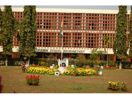 View of Sainik School Bhubaneswar, Odisha, showcasing its sprawling campus with modern academic buildings, sports fields, and lush greenery. Students in uniform are seen walking or engaged in various activities, with the backdrop of the peaceful surroundings and a disciplined atmosphere.