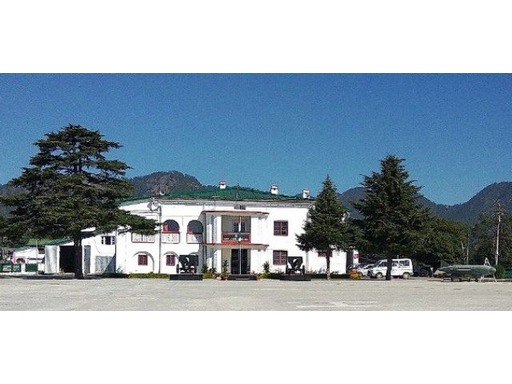 Panoramic view of Sainik School Ghorakhal, Uttarakhand, set amidst the picturesque hills. The campus features spacious academic buildings, sports fields, and lush green landscapes, with students in military uniforms walking along the pathways, reflecting a disciplined and serene atmosphere.